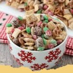 Close-up of festive Christmas Candy Crunch pieces on a white platter, adorned with holiday sprinkles, M&M's, and crushed candy canes.