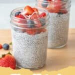 A glass jar of 3-Ingredient Chia Pudding topped with fresh berries and a drizzle of maple syrup.