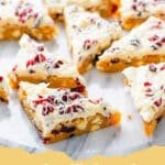 Close-up of freshly baked Cranberry Bliss Bars with white chocolate drizzle and dried cranberries, cut into squares.