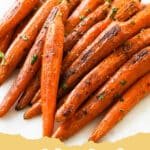 Pile of beautifully caramelized easy oven roasted carrots on a white plate, garnished with fresh parsley.