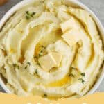 A bowl of exceptionally creamy and fluffy mashed potatoes, garnished with fresh chives and a swirl of melted butter.