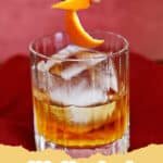 A classic Old Fashioned Cocktail in a rocks glass with a large ice cube and orange peel garnish.