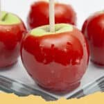 Unlock Childhood Memories: How to Make the BEST Candy Apples at Home! 5 Beautifully glossy, vibrant red candy apples on sticks resting on parchment paper.