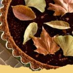 A beautiful slice of Pumpkin Pie with Chocolate Ganache, showing the distinct layers, garnished with whipped cream and chocolate shavings.