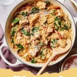 Close-up of a skillet filled with creamy lemon herb chicken orzo, garnished with fresh parsley and dill, with a lemon wedge on the side.